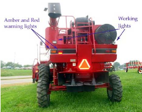 Photo 3: This combine shows a good SMV, amber and red retroreflective tape, and red and amber lights. Not visible are headlights. The working lights should not be used when traveling on public roadways. 