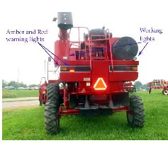 Photo 2: The combine utilizes a good SMV, amber and red retro reflective tape, and red and amber lights. Not visible are headlights. The working lights should not be used when traveling on public roadways.
