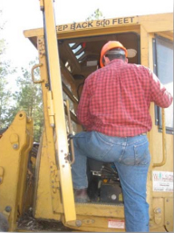 Photo of a man climbing into a vehicle cab.