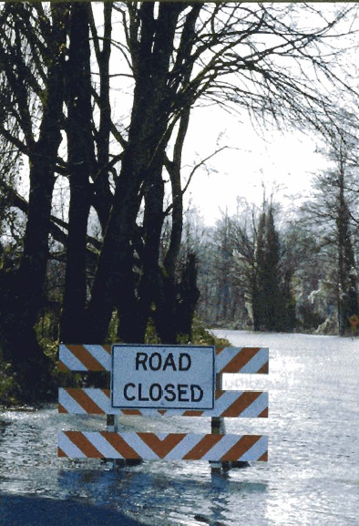 Photo of a barrier Road Closed sign in a flood