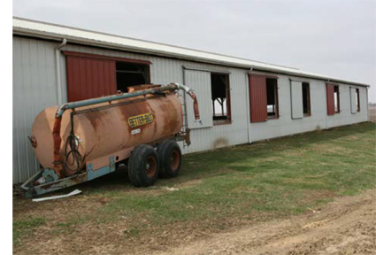 B. North side of shed with manure spreader tank outside building Windows with white panel covers were added after the fatalities