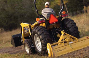 Photo of a man on a tractor hauling some equipment attached to his PTO