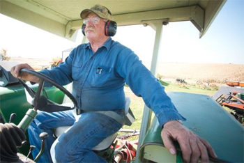 Photo of a farmer in a tractor cab wearing hearing PPE