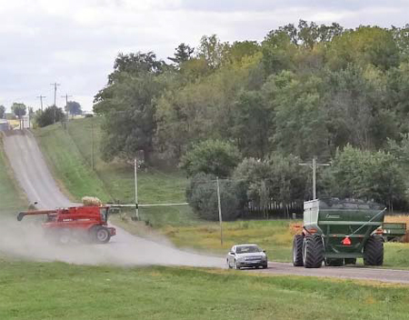 Photo of heavy farm equipment sharing the road with a vehicle