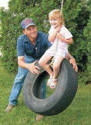 man pushing a girl on a tire swing